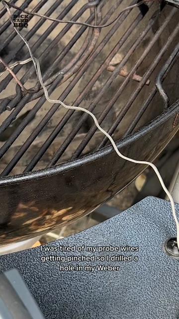 Weber Kettle Probe Port Mod I was tired of my probe wires getting pinched. So, I drilled a hole in my Weber Installed a grommet. And now my probes are out of the way, don’t get pinched, and I get a better seal. My Weber has a side table, so I removed that first to get a clear shot for my drill. I found a good spot for the port in the back, right below the kettle lip, and above the grate. I taped it off to help prevent the drill from slipping, drew a rough outline, marked center, and drilled a pilot hole. I used a step bit to get the hole to 1.25 inches.  I alternated between drilling from the outside and inside. You could paint that rough edge with high temp paint, but I’m not worried about it.  I just sanded it a little to remove any burrs.  I slit the eyes of my grommet so my probes could fit in easily.  I then lubed it up with some olive oil and maneuvered it into the hole. I reassembled the grill and sent a probe through the port and it worked out great.  Give this mod a try and let me know how it turns out.  It will probably void your warranty, but I’m not worried because I’m keeping this one forever. #bbq #bbqhacks #bbqtips #grilling